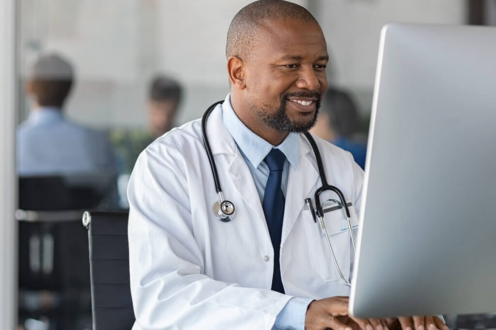 Doctor with lab coat, and stethoscope using computer.
